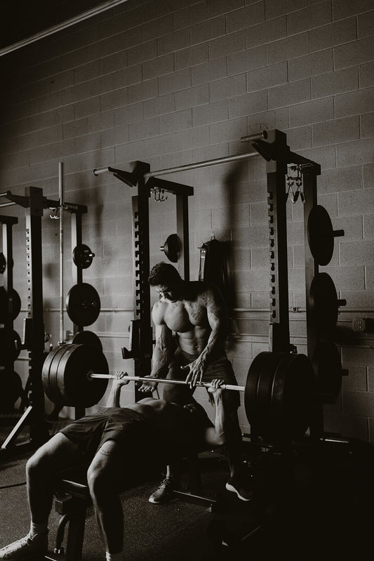 A meka athlete bench presses with a spotter